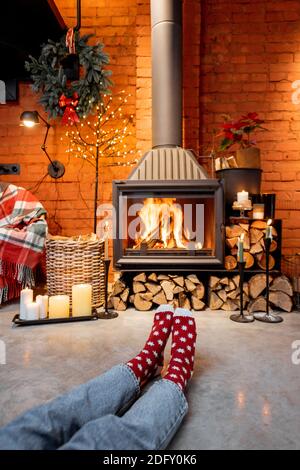 Femme en chaussettes de Noël près de la cheminée à la maison. Le concept de confort pendant les vacances d'hiver et de nouvel an Banque D'Images