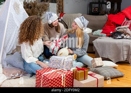 jeunes filles ayant plaisir emballer des cadeaux à la maison, grand travail d'équipe d'amis emballer des cadeaux pour noël, se préparer pour le prochain an et noël Banque D'Images