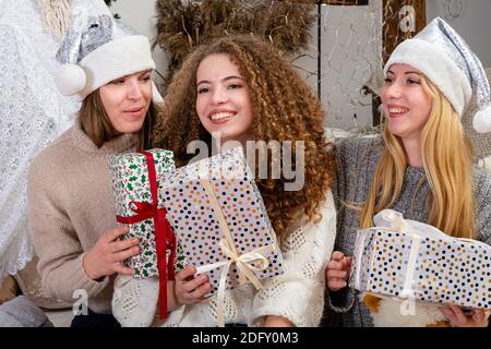 jeunes filles ayant plaisir emballer des cadeaux à la maison, grand travail d'équipe d'amis emballer des cadeaux pour noël, se préparer pour le prochain an et noël Banque D'Images