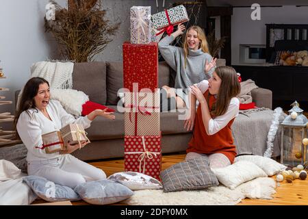 jeunes filles ayant plaisir emballer des cadeaux à la maison, grand travail d'équipe d'amis emballer des cadeaux pour noël, se préparer pour le prochain an et noël Banque D'Images