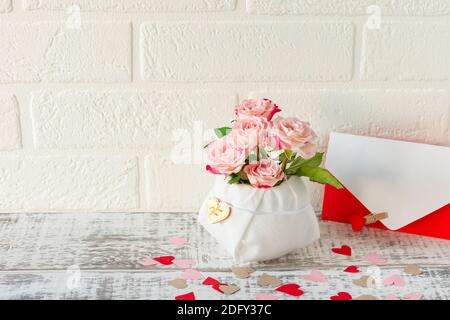 Arrangement festif de bouquet de roses roses et enveloppe avec lettre de bienvenue pour les vacances. Banque D'Images