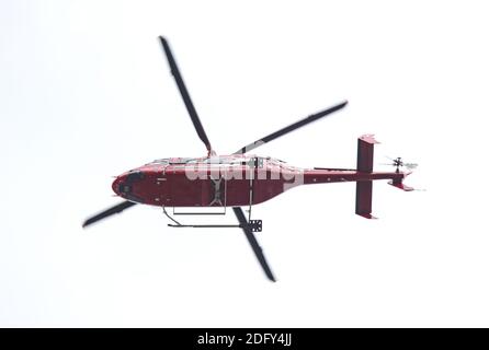 Hélicoptère rouge isolé dans le ciel, volant de droite à gauche Banque D'Images