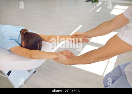 Mains de l'homme chiropracteur tirant lyong femme patients mains à fixer son dos et son articulation d'épaule Banque D'Images