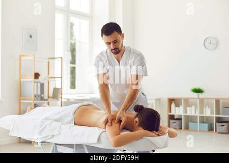 Masseuse professionnelle faisant un massage thérapeutique du corps pour la jeune femme couché sur la table de massage Banque D'Images