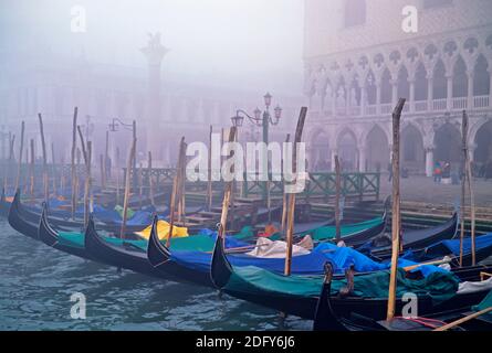 Venise une vue sur la place Saint Marks sur amarré les gondoles dans la brume matinale sur leurs poteaux d'amarrage avec mise au point de premier plan Banque D'Images