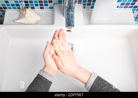 Enfant se sope diligemment les mains effectuant le lavage des mains - mesure de protection de base Contre la propagation du coronavirus COVID-19 Banque D'Images