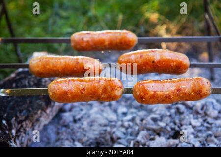 Saucisses frites sur brochettes. Soirées d'été près du feu, bon week-end. Gros plan Banque D'Images