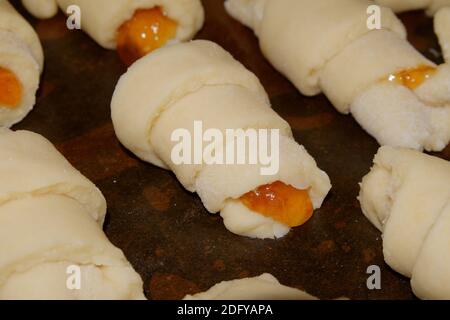 Biscuits faits maison roulés dans un tube avec remplissage de confiture sur une plaque de cuisson avec un dos de papier humidifié avec de l'huile végétale. Mise au point sélective. Banque D'Images