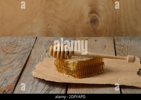 Miel en nid d'abeille et cuillère sur papier d'emballage sur une table en bois. Mise au point sélective. Banque D'Images