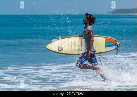 VARKALA, INDE - 14 mars 2020 : un surfeur indien de sexe masculin qui coururiousltowards l'océan pour attraper les vagues Banque D'Images