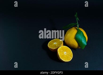 Coupe de mandarine avec une feuille verte sur fond noir Banque D'Images