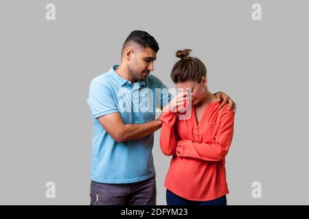 Portrait de jeune couple inquiet malheureux dans des vêtements décontractés, réconfortant de pleurer femme, tenant ses épaules, l'expression de condoléances. Banque D'Images