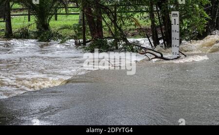 Route inondée après de fortes pluies d'été. Ruisseau traversant la route, Queensland, Australie. Banque D'Images