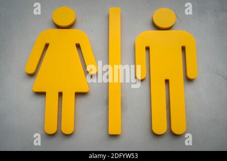 Jaune côte à côte femme et homme symboles de public panneau des toilettes sur un mur en béton Banque D'Images