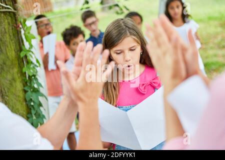 Le public applaudit les filles qui chantent en solo lors d'un spectacle de talents l'été camp Banque D'Images