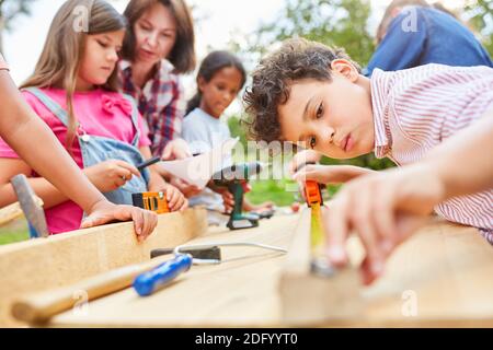 Les enfants font de l'artisanat et travaillent avec du bois dans l'atelier au camp de vacances Banque D'Images