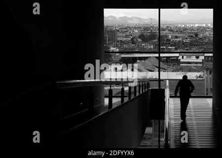 Photo en niveaux de gris d'un homme qui descend les escaliers d'un bâtiment Banque D'Images