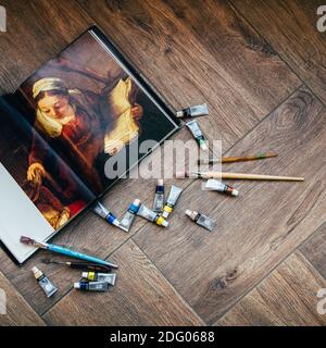 Les peintures à l'huile, les pinceaux et un livre sur les artistes se trouvent sur la tuile, l'endroit pour le texte Banque D'Images