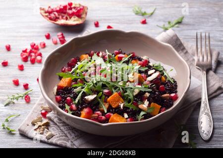 Salade avec riz noir, citrouille cuite au four, graines de grenade, arugula et noix sur fond gris. Délicieux repas végétalien Banque D'Images