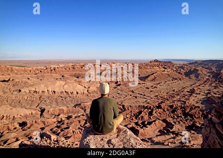 Randonneur assis sur la falaise Rocky Cliff en admirant l'incroyable paysage Vallée de la Lune ou Valle de la Luna à Atacama Désert du Chili Banque D'Images