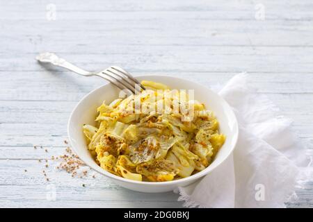 Chou chinois mariné à l'ail et aux épices, moutarde, curcuma, piment dans un bol blanc sur fond bleu, sélectif. Oriental sain Banque D'Images