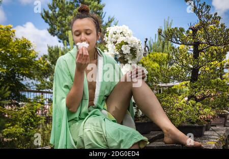 Jardin japonais. Jeune belle femme habillée de kimono japonais au jardin, profitant de la beauté de la nature et des fleurs en fleurs Banque D'Images