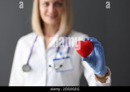 Docteur en gants de caoutchouc tenant le coeur rouge jouet dans son gros plan des mains Banque D'Images