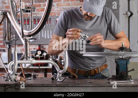 l'homme répare la bicyclette vintage dans l'atelier de garage sur l'établi avec des outils, concept de bricolage Banque D'Images