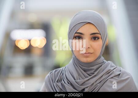 Portrait en gros plan d'une belle femme du Moyen-Orient portant un foulard gris tout en étant debout en ville avec un arrière-plan flou, espace de copie Banque D'Images