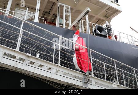 Rostock, Allemagne. 07ème décembre 2020. Vêtu de Saint Nicholas, Stefanie Zernikow, une déaconesse de marin, monte à bord du cargo Jy Shanghai dans le port maritime pour apporter un arbre de Noël. Pour l'action traditionnelle de la mission des marins 'Hollfast', le centre de jardin Rostock 'Grönfingers' a donné les firs Nordmann. Credit: Bernd Wüstneck/dpa-Zentralbild/dpa/Alay Live News Banque D'Images