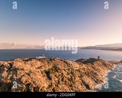 Vue aérienne du soleil tôt le matin sur le phare et Tour génoise à la Pietra en Ile Rousse dans le Balagne région Corse avec le désert des A. Banque D'Images