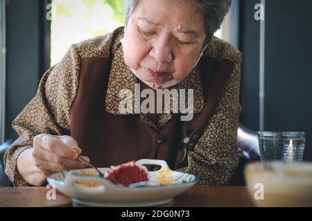 vieille asiatique âgée aînée femme mangeant cheesecake au restaurant. mode de vie de retraite mature Banque D'Images