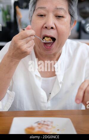 vieille femme asiatique âgée aînée mangeant un gâteau au restaurant. mode de vie de retraite mature Banque D'Images