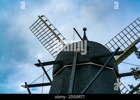 Vieux moulin à vent en bois noir utilisé pour moudre la farine dans le passé. Avec nuages et ciel bleu en arrière-plan. Banque D'Images