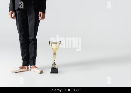 vue écourtée de la femme d'affaires afro-américaine dans les chaussures pointe avec golden cup sur gris Banque D'Images