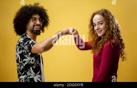Homme mature et jeune femme dans un studio sur fond jaune, salutation. Banque D'Images