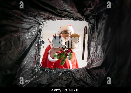 Le Père Noël jette des cadeaux et des décorations de Noël dans les poubelles. Vue de la benne. Banque D'Images