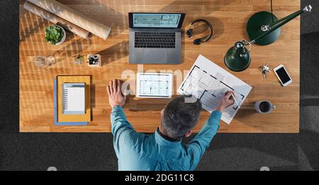 Vue de dessus d'un architecte d'affaires travaillant sur un ordinateur au bureau avec des papiers dans le bureau à la maison. Banque D'Images
