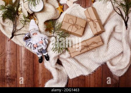 Composition hivernale confortable. Style d'hygge. Cadeaux de Noël, décorations rustiques, guirlande étoiles dorées et chandail chaud sur fond de bois. Pose à plat, à Banque D'Images