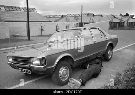Milton Keynes New Town homme des années 1970 travaillant au bord de la route sur sa voiture à faire quelques réparations. Lotissement moderne 1977 UK Milton Keynes, Buckinghamshire HOMER SYKES Banque D'Images