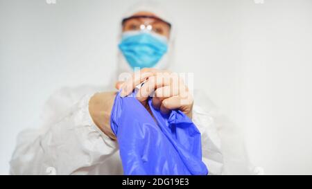 Le travailleur médical en costume de protection met des gants. Banque D'Images