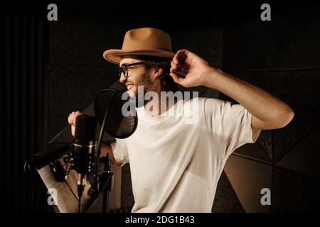 Beau musicien élégant dansant et chantant tout en enregistrant de nouveaux chanson dans un studio moderne Banque D'Images