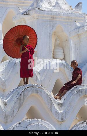 Jeunes moines bouddhistes novices, dont l'un tient un parasol à la Pagode Myatheindan (également connue sous le nom de Pagode Hsinbyume), Mingun, Myanmar (Birmanie), Asie en février Banque D'Images