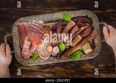 Divers types de charcuterie appétissante sur un élégant plateau arrière-plan, ancienne table en bois Banque D'Images