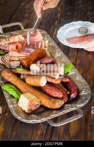 Divers types de charcuterie appétissante sur un élégant plateau arrière-plan, ancienne table en bois Banque D'Images