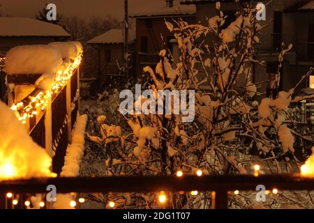 Des lumières de Noël s'illuminent sur le balcon d'une cabane, filmée dans toute leur splendeur lors d'une forte chute de neige. Fond romantique et adapté aux cartes de Noël Banque D'Images