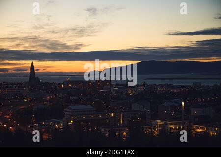 Belle vue nocturne de Reykjavik, Islande, vue aérienne avec l'église luthérienne de Hallgrimskirkja, avec des paysages au-delà de la ville, la montagne Esja et fax Banque D'Images