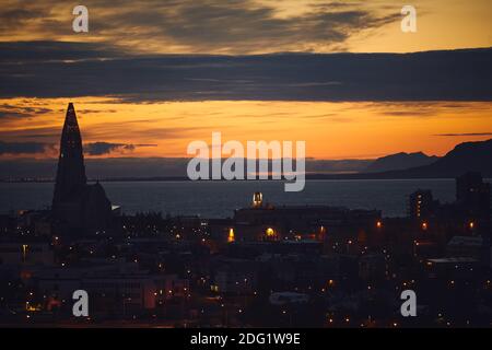 Belle vue nocturne de Reykjavik, Islande, vue aérienne avec l'église luthérienne de Hallgrimskirkja, avec des paysages au-delà de la ville, la montagne Esja et fax Banque D'Images