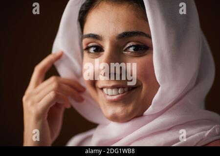 Gros plan de la belle femme du Moyen-Orient portant un voile et souriant à la caméra en posant en studio, dans un espace de copie Banque D'Images