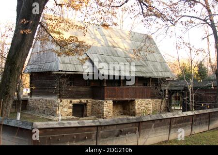 Musée du village, Bucarest, Roumanie. Maison en bois du XIXe siècle du comté de Sibiu, avec toit en ardoise en bois, balcon, fondation en pierre et cave. Banque D'Images